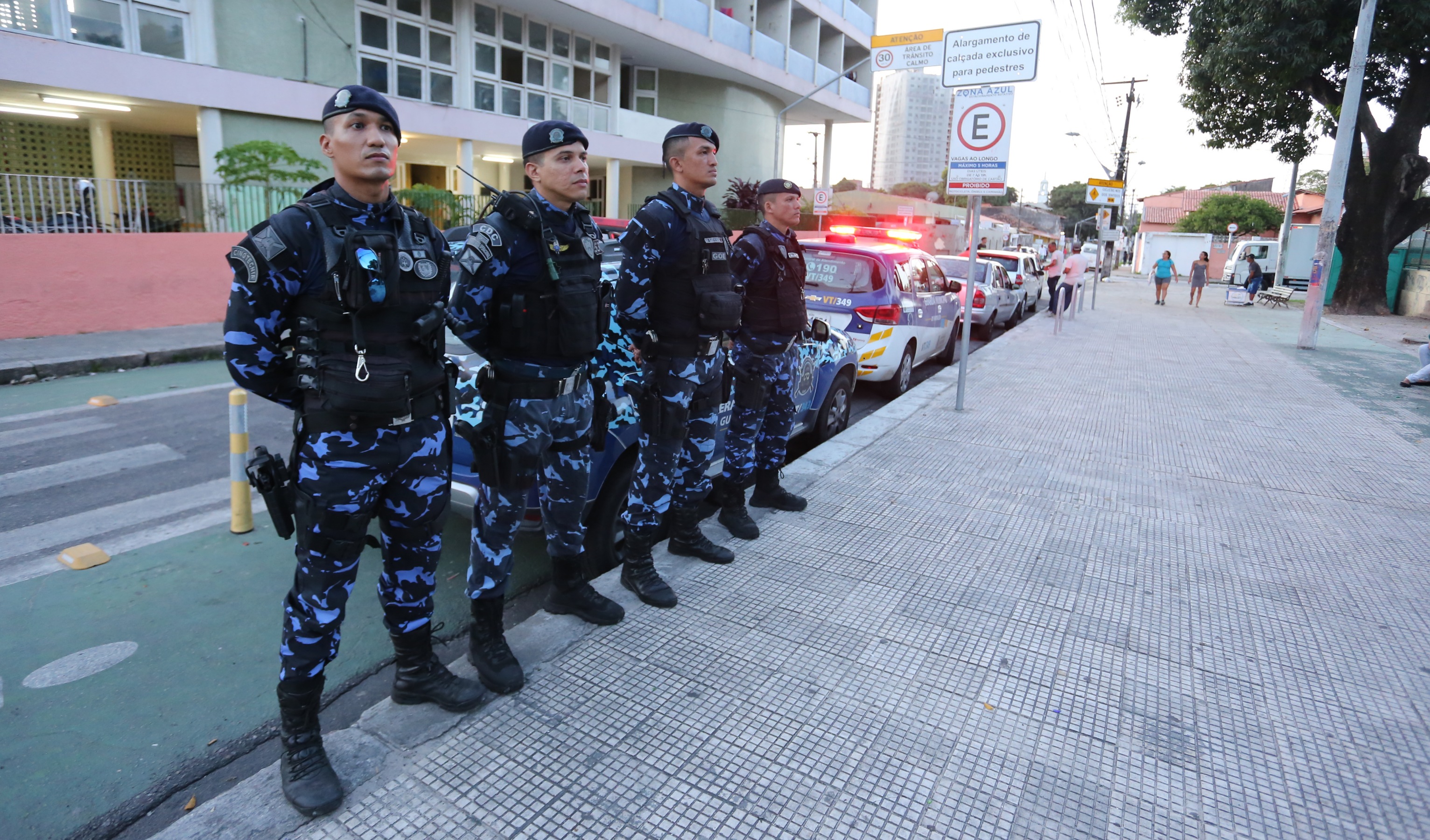 guardas municipais em pé em calçada de praça
